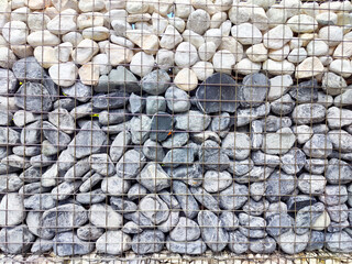 Decorative stone wall constructed with gray and white pebbles in a modern outdoor setting