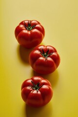 three fresh ripe red juicy tomatoes on a yellow background.