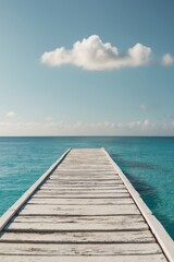 Obraz premium A wooden dock leading to clear blue ocean waters under a sunny sky.