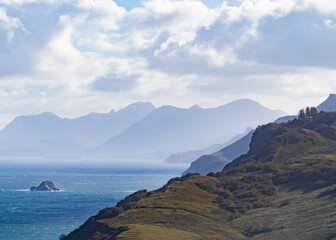View over hills across the sea to misty mountains beyond