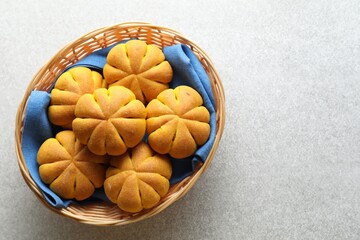 Wicker basket with tasty pumpkin shaped buns on light table, top view. Space for text