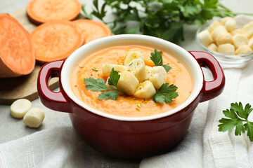 Delicious sweet potato soup with croutons and parsley on light table, closeup