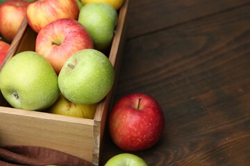 Fresh ripe apples in crate on wooden table, closeup. Space for text