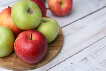 Different whole ripe apples on white wooden table, closeup. Space for text
