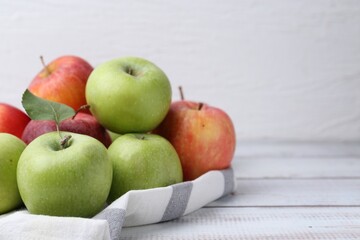 Different whole ripe apples on white wooden table, closeup. Space for text