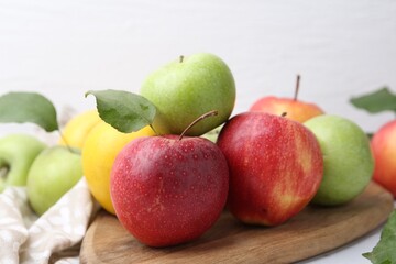 Different whole ripe apples on wooden table, closeup