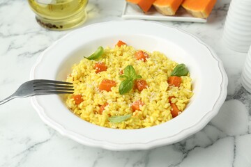 Delicious pumpkin risotto served on white marble table, closeup