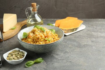 Delicious pumpkin risotto with basil on grey table