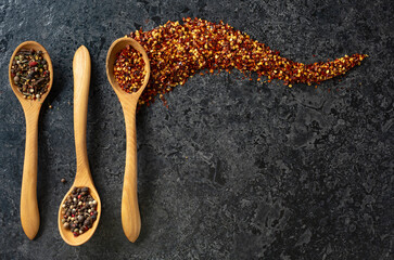 Chili flakes and mix of organic dried spices in wooden spoons.