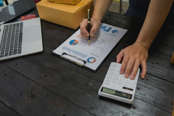 An Asian man carefully prepares a package for a customer's online order, methodically placing items in a box, sealing it securely, and attaching a shipping label for prompt delivery.