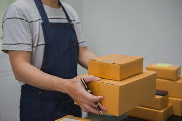 An Asian man carefully prepares a package for a customer's online order, methodically placing items in a box, sealing it securely, and attaching a shipping label for prompt delivery.