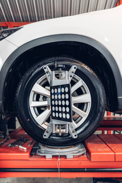 Car wheel centering machine adjustment. Auto service mechanic installing wheel alignment sensor on tire during vehicle suspension alignment adjustment