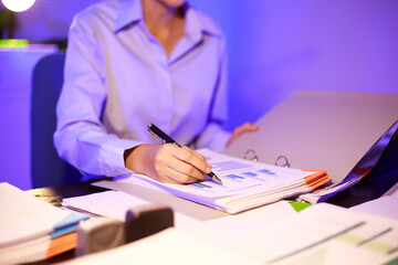 Asian woman diligently works overtime, managing a heavy workload with focus and determination. Despite the challenges, her commitment shines through as she strives  and meets her deadlines.