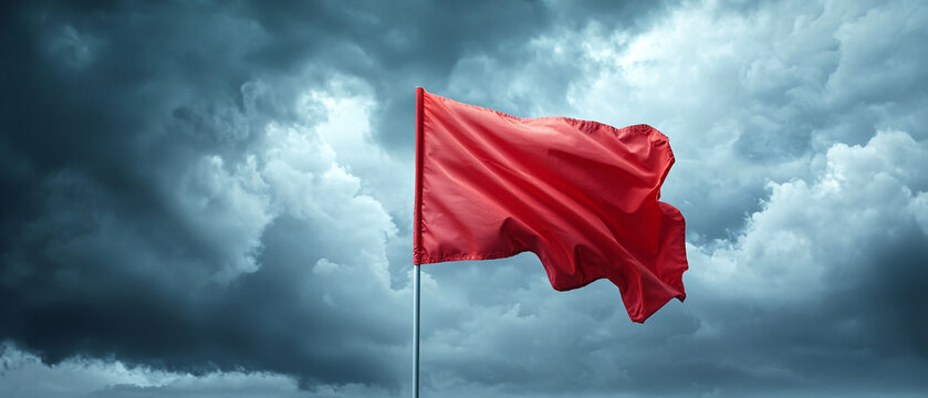 Red flag waving in stormy sky, signaling caution and danger