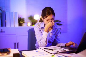 Asian woman diligently works overtime, managing a heavy workload with focus and determination. Despite the challenges, her commitment shines through as she strives  and meets her deadlines.