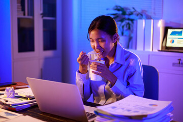 Asian woman diligently works overtime, managing a heavy workload with focus and determination. Despite the challenges, her commitment shines through as she strives  and meets her deadlines.