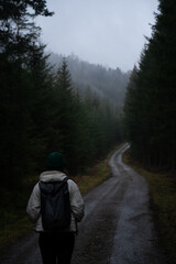 Woman walking on moody road in rainy forest
