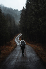 Woman walking on moody road in rainy forest