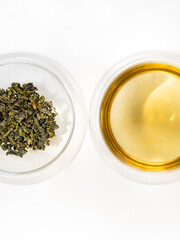Top view of green tea leaves and drink in  transparent glass cup isolated on  white background. Milk oolong tea. 