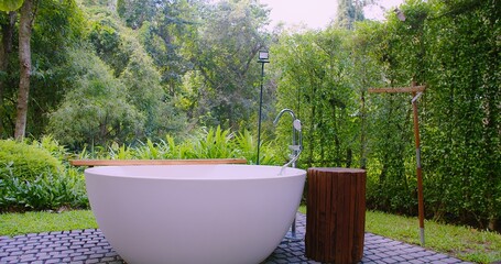 A modern outdoor bathtub in a tranquil garden, offering a peaceful escape surrounded by lush greenery, tropical garden serene and relaxing ambiance. eco-friendly resorts or wellness retreats.