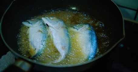 Crispy Fried mackerel Fish frying in a pan on a Stove in a Rustic Kitchen, sizzling in hot oil, showcasing a delicious home-cooked meal.