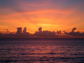 Naklejka premium Vibrant orange and pink hues of the setting sun over a calm ocean, beauty, ocean