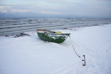 Winter landscape from the seashore,.  Fisherman boat on the seashore,  ice texture in Winter. 