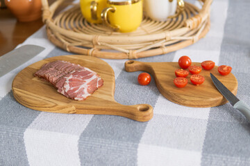 cherry tomatoes and sliced ham on a cutting boards on a table