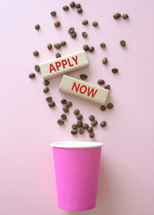 Apply now symbol. Concept word Apply now on wooden blocks. Beautiful pink background with coffee cup. Business and Apply now concept. Copy space