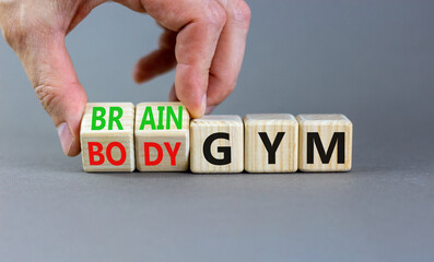 Body vs brain gym symbol. Businessman turns wooden cubes and changes words Body gym to Brain gym. Beautiful grey background, copy space. Business and body vs brain gym concept.