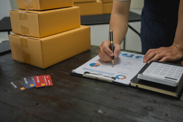 An Asian man carefully prepares a package for a customer's online order, methodically placing items in a box, sealing it securely, and attaching a shipping label for prompt delivery.