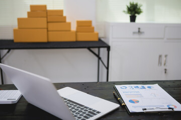 An Asian man carefully prepares a package for a customer's online order, methodically placing items in a box, sealing it securely, and attaching a shipping label for prompt delivery.
