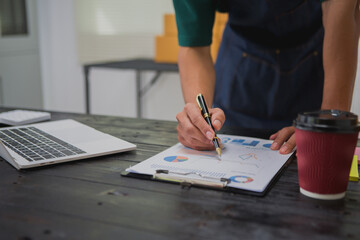 An Asian man carefully prepares a package for a customer's online order, methodically placing items in a box, sealing it securely, and attaching a shipping label for prompt delivery.