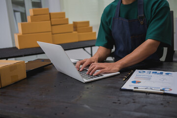 An Asian man carefully prepares a package for a customer's online order, methodically placing items in a box, sealing it securely, and attaching a shipping label for prompt delivery.