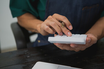 An Asian man carefully prepares a package for a customer's online order, methodically placing items in a box, sealing it securely, and attaching a shipping label for prompt delivery.