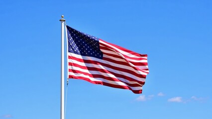 Fototapeta premium Waving American flag against a clear blue sky during daylight, symbolizing patriotism and national pride