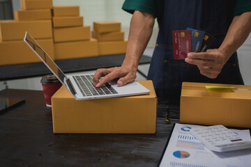 An Asian man carefully prepares a package for a customer's online order, methodically placing items in a box, sealing it securely, and attaching a shipping label for prompt delivery.