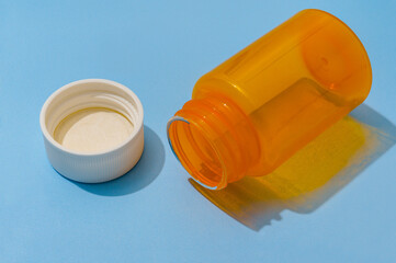 Empty Orange Pill Bottle and White Cap on Blue Background