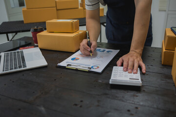 An Asian man carefully prepares a package for a customer's online order, methodically placing items in a box, sealing it securely, and attaching a shipping label for prompt delivery.
