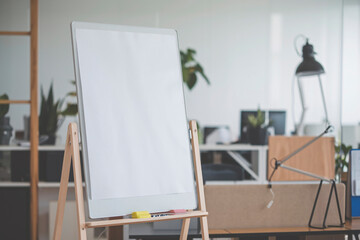 Blank Flipchart Paper in Office Meeting Room Setting. A blank sheet of flipchart paper pinned to a board in a modern office meeting room.