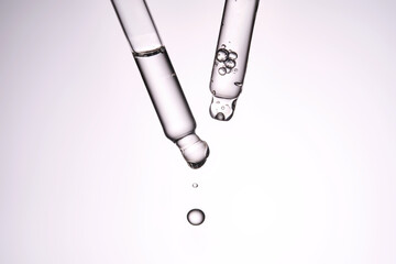 Two pipettes with a cosmetic product. Serum or fluid drips from one of them.
