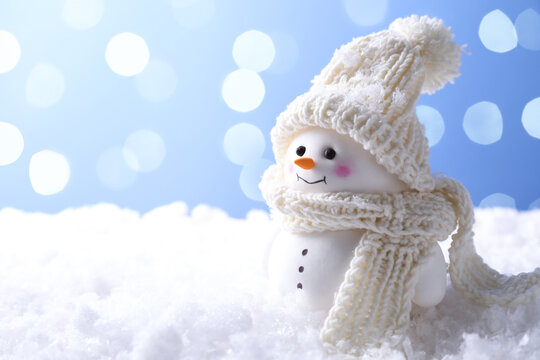 Cute decorative snowman on artificial snow against light blue background, space for text - Powered by Adobe