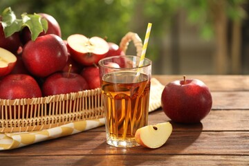 Tasty apple juice in glass and fresh fruits on wooden table outdoors