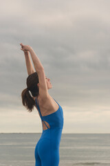 sporty woman swimmer doing an arm stretch above her head at the beach
