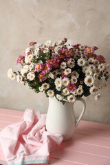Vase with beautiful flowers and cloth on pink wooden table