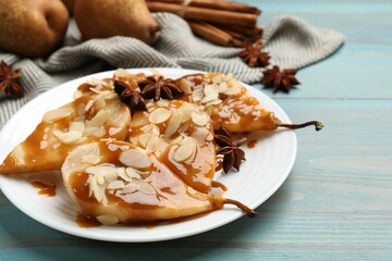 Delicious pears with caramel sauce, almond flakes and anise stars on light blue wooden table, closeup