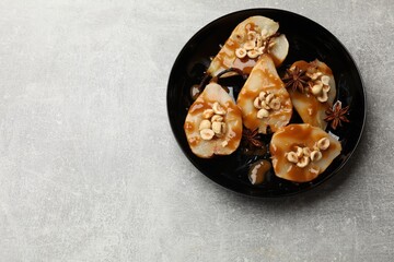 Delicious pears with caramel sauce, nuts and anise stars on grey table, top view. Space for text