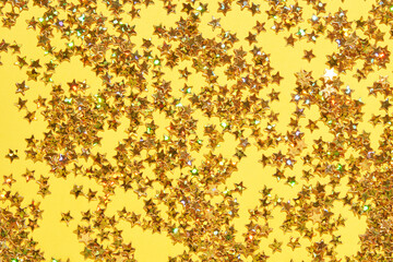 Vibrant gold star confetti on yellow background for festive celebrations and party decor.