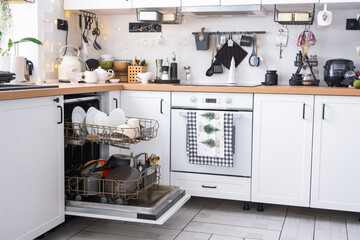 A lot of dirty dishes in the dishwasher in the festive kitchen. Helping the hostess, economy and ecology. Cleaning in the kitchen for the holidays of Christmas and New Year, after the feast and guests