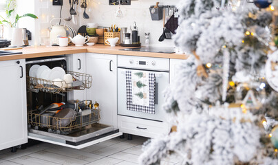 A lot of dirty dishes in the dishwasher in the festive kitchen. Helping the hostess, economy and ecology. Cleaning in the kitchen for the holidays of Christmas and New Year, after the feast and guests